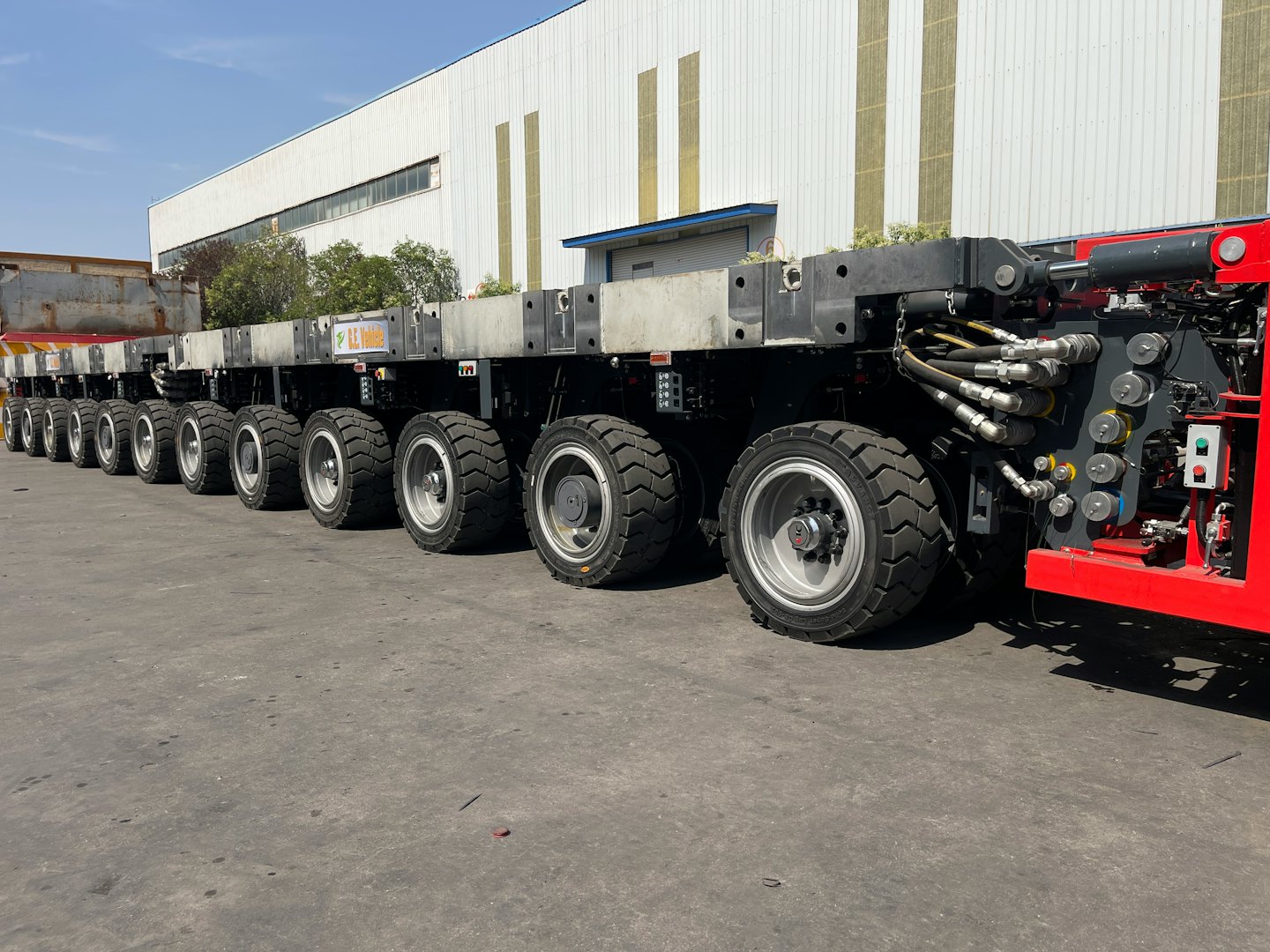Schwerlast-Modultransporter neben einem Industriegebäude.
