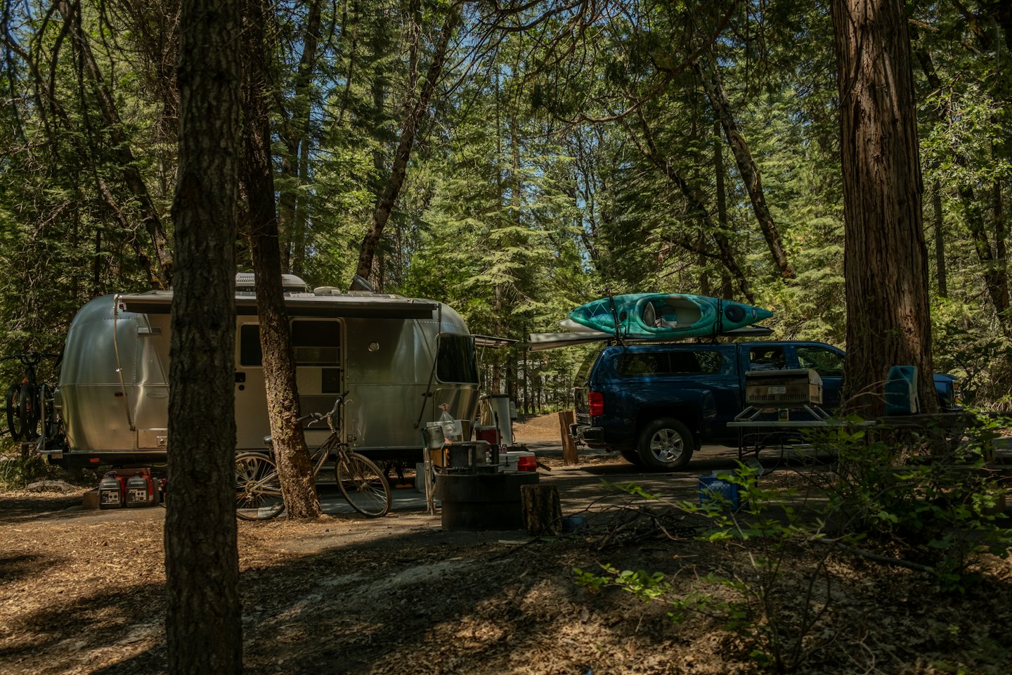 Silberner Airstream-Wohnwagen und Pickup-Truck auf einem Campingplatz.