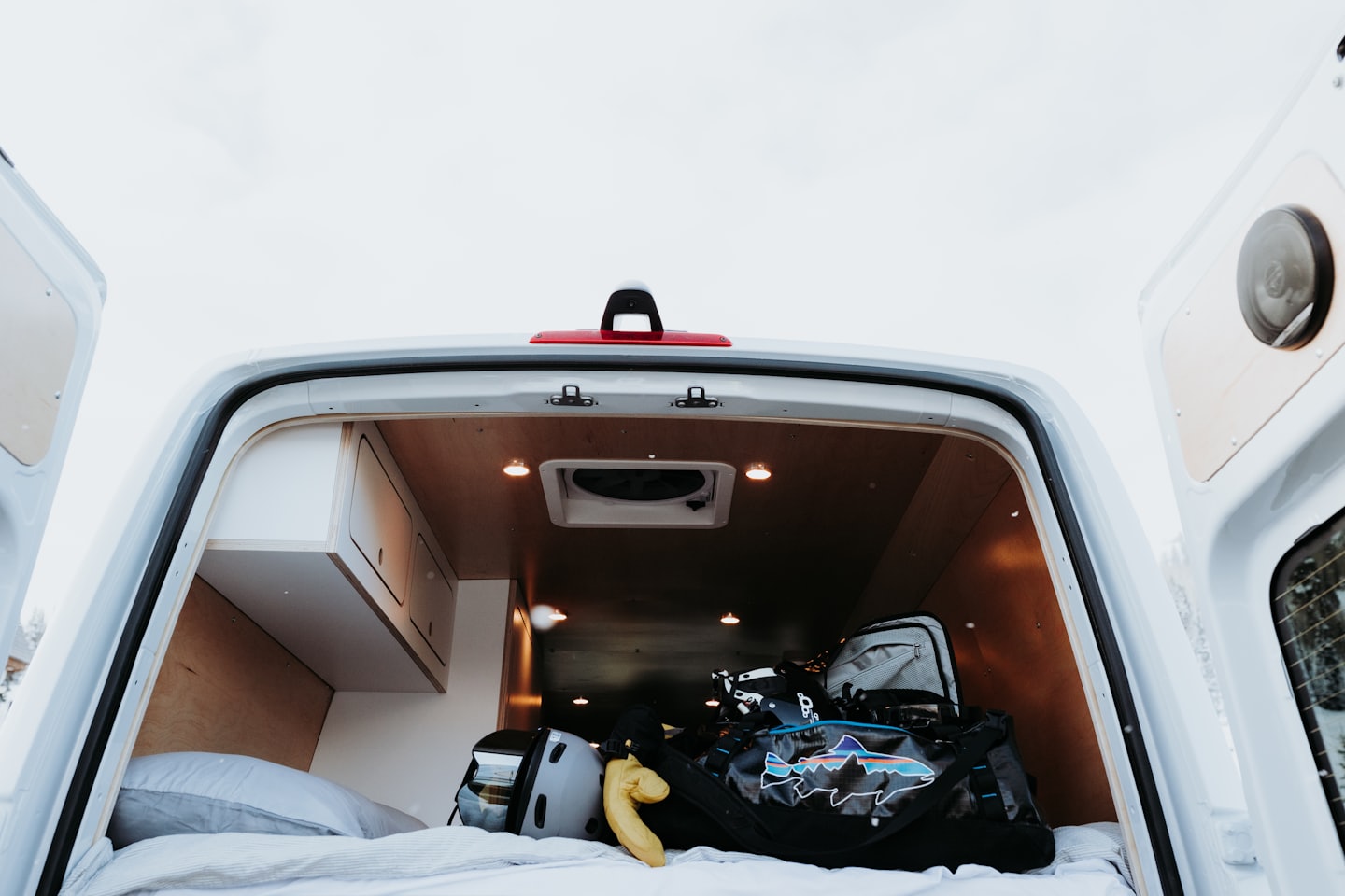 Innenraum eines Campervans mit Stauschränken und Bett.