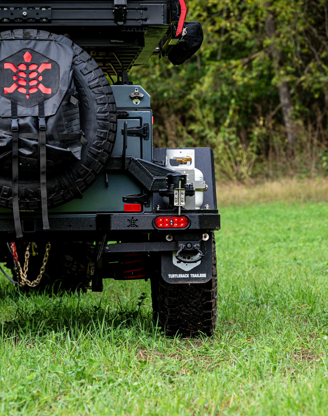 Dunkelgrüner Geländewagen-Anhänger auf Gras geparkt.